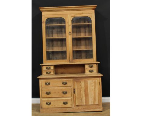 A farmhouse pine dresser, outswept cornice above a pair of glazed doors enclosing three shelves, the base with an arrangement