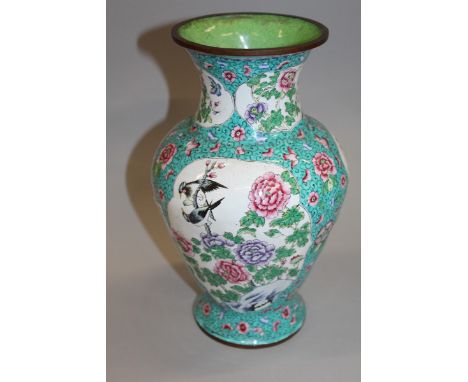 AN EARLY 20TH CENTURY CHINESE CANTON ENAMEL VASE, the sides decorated with shaped panels of birds and foliage reserved on a t