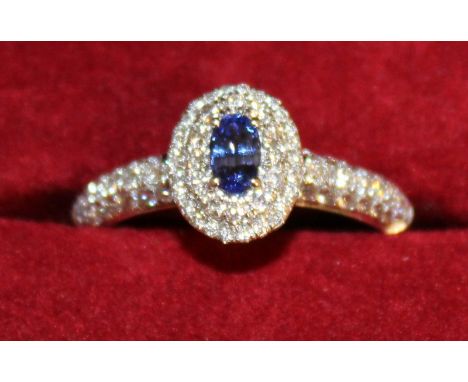 A SAPPHIRE AND DIAMOND CLUSTER RING with diamond shoulders, set in 18ct white gold.