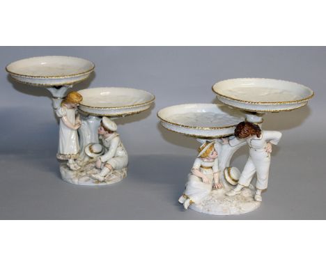 A GOOD PAIR OF HADLEYS ROYAL WORCESTER COMPORTS, after KATE GREENAWAY, formed as a young boy and girl holding up circular com