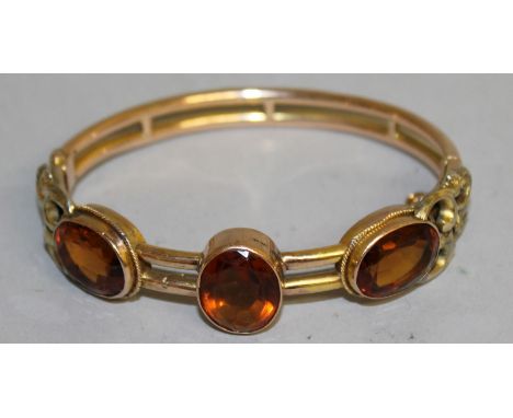 A VICTORIAN GOLD BANGLE inset with three cut glass stones.