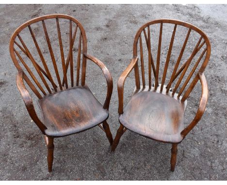 A pair of elm seated comb back elbow chairs.The first example with loose arm, split to top left corner of seat, scratches to 