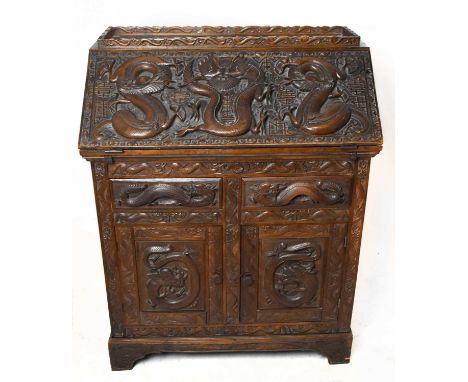 An Eastern profusely carved hardwood bureau, the fall front carved in high relief with coiled dragons enclosing a simple inte