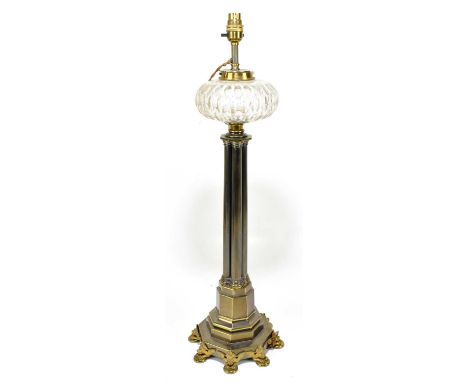 A Gothic inspired brass oil lamp with clear cut glass reservoir, cluster central column to a octagonal shaped mask adorned ba