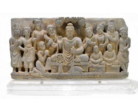 An early Sino-Tibetan carved stone panel showing a central deity with attendants by its side now mounted on a modern perspex 