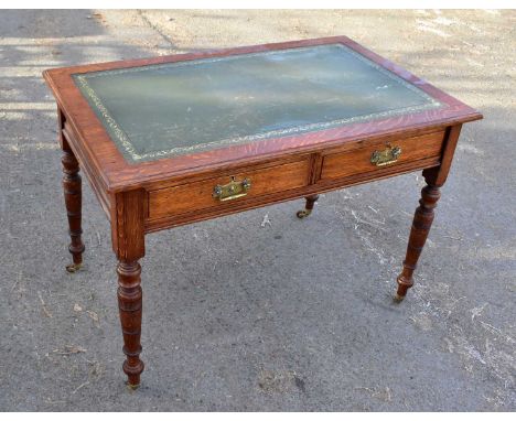An Edwardian oak writing table, the leather lined top above two frieze drawers on ring turned supports, width 107cm.The leath