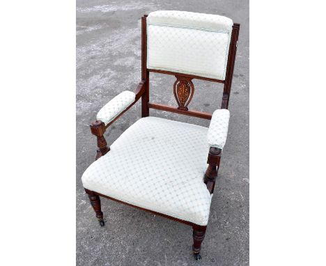 An Edwardian inlaid mahogany open armchair on ring turned supports.