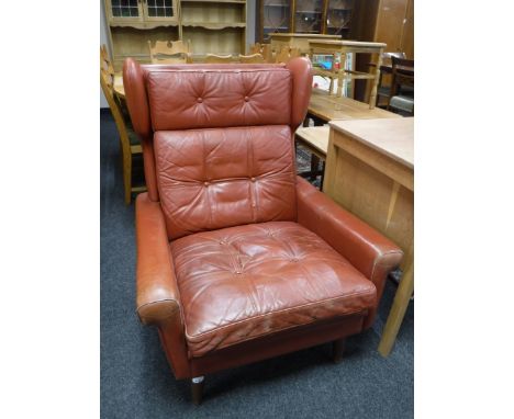 A mid 20th century red button leather wing back armchair 