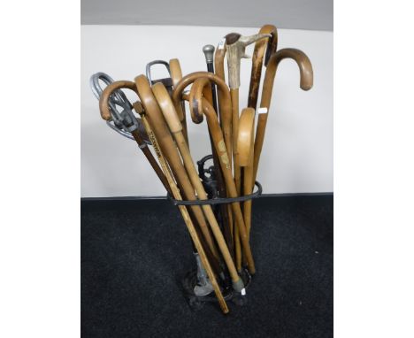 A cast iron stick stand, containing a quantity of walking sticks, together with two shooting sticks and a vintage shovel 