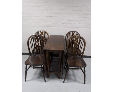 An oak gate leg table, together with a set of four wheel back chairs 