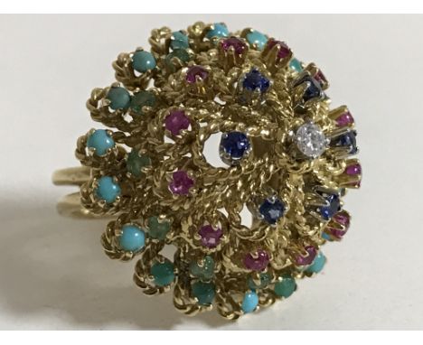 A high carat gold multi-gemstone ring, set with tiers of turquoise, emeralds, rubies, sapphires around a central brilliant cu