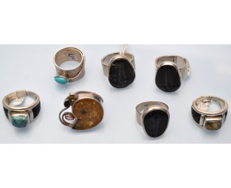 A fossil set ring; together with three other fossil rings; two turquoise set rings; and another ring.  (7)