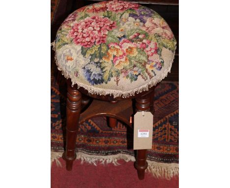 A Victorian mahogany circular music stool, having floral tapestry upholstered revolving seat and raised on ring turned suppor