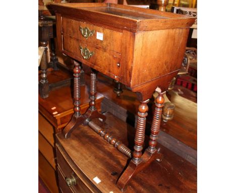 A Continental mahogany two drawer work table, having integral tray top, and raised on double ring turned end supports, united