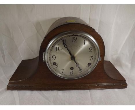 An oak cased Napoleon hat style mantel clock, the case having applied moulded decoration, silvered dial with Arabic numerals 