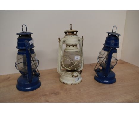 A vintage metal Swallow oil lantern in cream colour, h26cm, sold together with two other blue oil lanterns of similar style, 