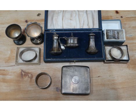 A group of 20th century silver items, including cigarette case of curved form with engine turned decoration, a cruet set of m