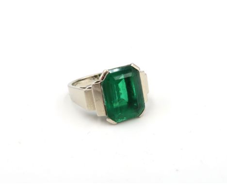 A stunning Art Deco style emerald single stone ring. The octagonal emerald estimated 4.12cts, to the stepped shoulders. Tests