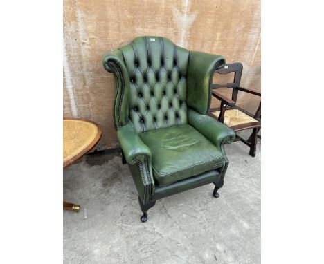 A GREEN LEATHER WINGED BUTTON BACK FIRESIDE CHAIR ON CABRIOLE LEGS