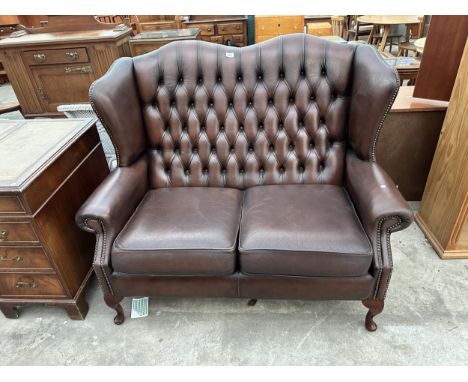 A BROWN LEATHER BUTTON BACK AND STUDDED WINGED TWO SEATER SETTEE ON CABRIOLE LEGS