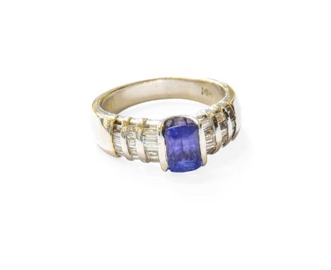 A Tanzanite and Diamond Ring, the rectangular cushion cut tanzanite flanked by stepped tapered baguette cut diamonds, in whit