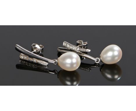 Pair of 14 carat white gold pearl earrings, with a pearl drop to each and a side of round cut diamonds, 31mm long