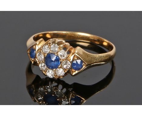 Sapphire and diamond set ring, with three round sapphires, the central sapphire with a diamond surround on a yellow metal sha