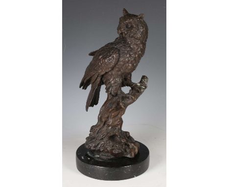 A 20th century cast bronze model of an owl perched on a branch, raised on a black hardstone base, height 43cm.