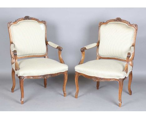 A pair of mid-20th century French Louis XV style walnut showframe fauteuil armchairs, height 97cm, width 65cm, depth 62cm.