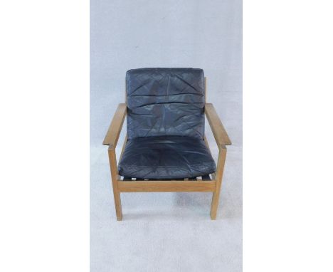 A mid century vintage teak framed armchair with black leather seat and back cushions. 77x70cm 