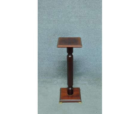 A small 20th century mahogany jardiniere stand with reeded column resting on brass bracket feet. H.66cm 