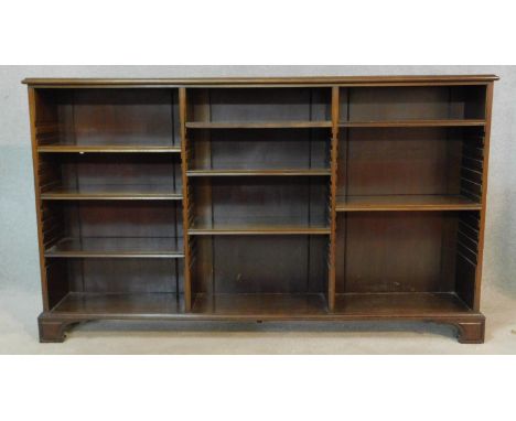 An early 20th century mahogany dwarf library bookcase with three sections of adjustable shelves on shaped and carved bracket 