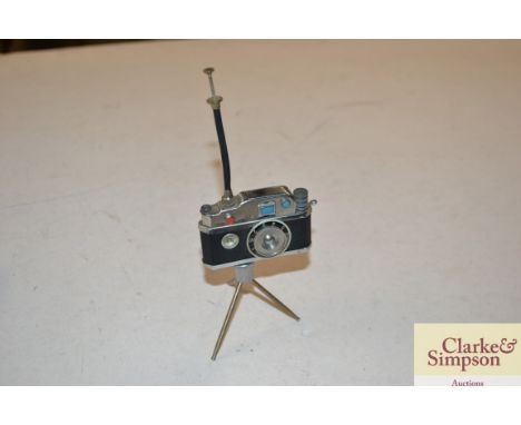A novelty lighter in the form of a camera and folding tripod with integral compass