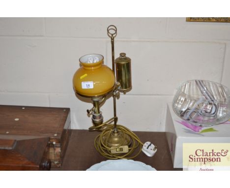 A brass oil lamp converted to electricity with glass shade
