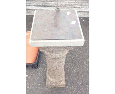 A garden sundial with etched brass plate and nomen set on a faux granite reconstituted stone column base