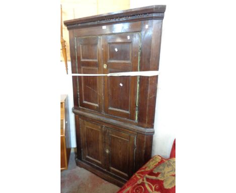 A 1.15m antique oak corner cabinet with remains of dentil cornice, canted sides and painted scalloped shelf interior enclosed