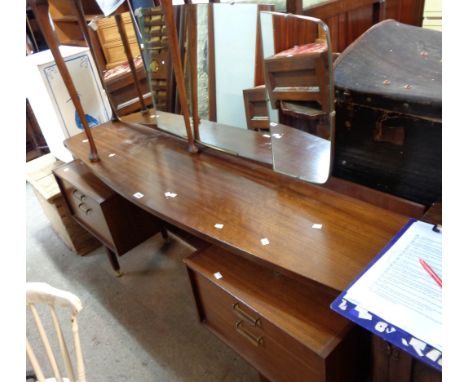 A 1.6m early G-Plan mixed wood bow front dressing table with triple mirror, central shelf and flanking drawers, set on ebonis