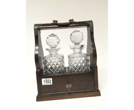 A two bottled cut glass decanter tantalus with a mahogany frame and key.