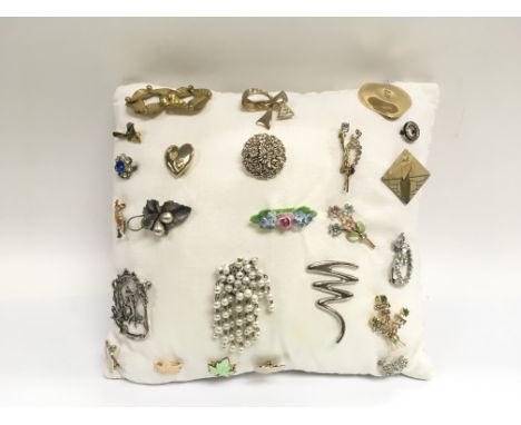 A collection of brooches presented on a cushion.