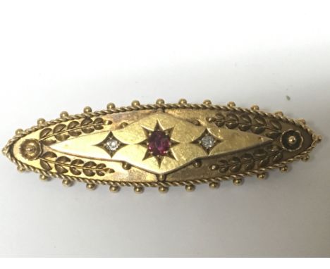 A vintage 15carat gold brooch set with ruby flanked by two diamonds. Weight 4g