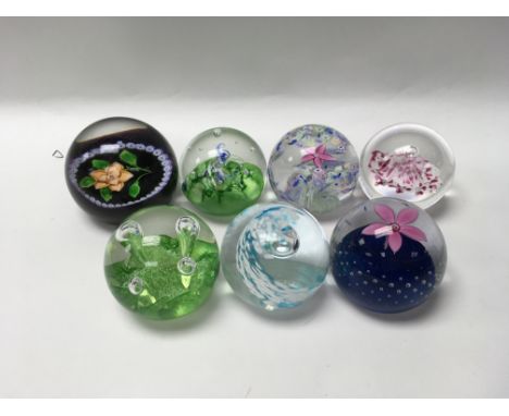 A collection of seven glass paper weights including Caithness.