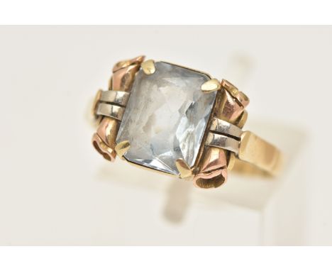 A YELLOW METAL GEM SET RING, set with a light blue rectangular stone assessed as blue spinel (very worn facet edges), scrolli