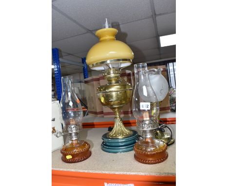 A GROUP OF VINTAGE OIL LAMPS, comprising two mid - 20th century, clear glass chimney, an amber glass base lamps, with metal b