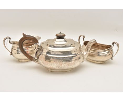 A GEORGE V SILVER THREE PIECE TEA SET, comprising of a teapot, milk jug and a sugar bowl, the teapot fitted with a light wood