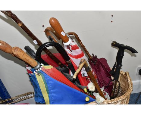 A BASKET OF WALKING STICKS AND UMBRELLAS, to include an antler handled riding crop, an Antishock walking pole, a natural wood