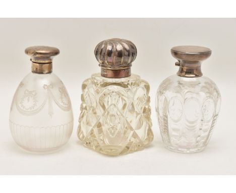 THREE GLASS SCENT BOTTLES, the first a frosted glass bottle with bow detail, fitted with a hinged silver cover and glass stop