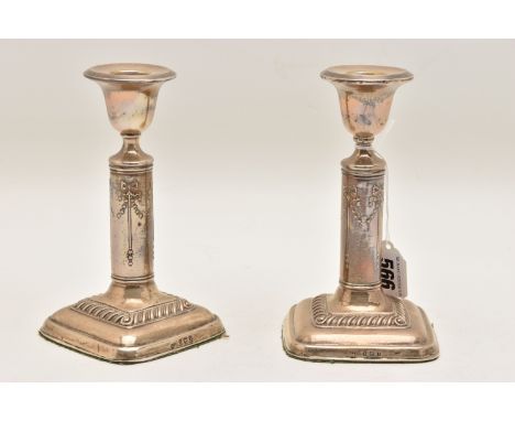 A PAIR OF EARLY 20TH CENTURY SILVER CANDLESTICKS, step detail to the drip pans, bow detail to the stems, on square weighted b