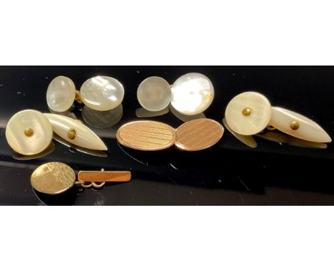 A 9ct rose gold engine turned single cuff link, a 9ct gold single cuff link, 4.7g; a pair of mother-of-pearl cuff links, anot