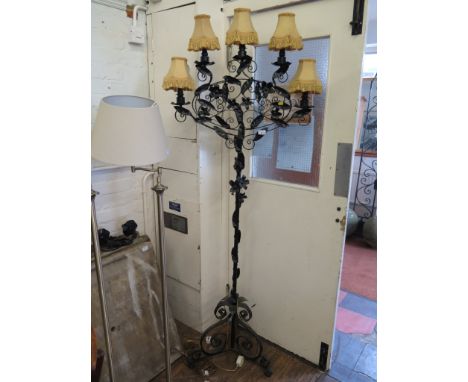 A wrought iron standard lamp, with five lights on a scroll frame applied with leaves and flowers on a scrolling tripod base, 