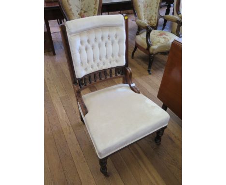 An Edwardian walnut nursing chair, the button upholstered back with spindle turned rail above an overstuffed seat, turned tap